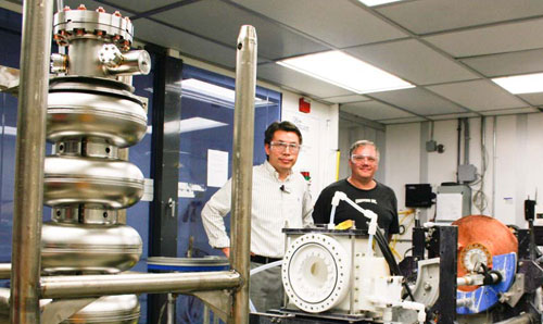 JLab's Rongli Geng and Fermilab's Jim Follkie stop for a photo in the SRF Electro-Polishing Lab. The milestone achieving cavity, AES8, is sitting in the left foreground