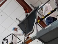 Tyler Lemon and Pablo Campero lifting electronics panel frame over detector assembly frame