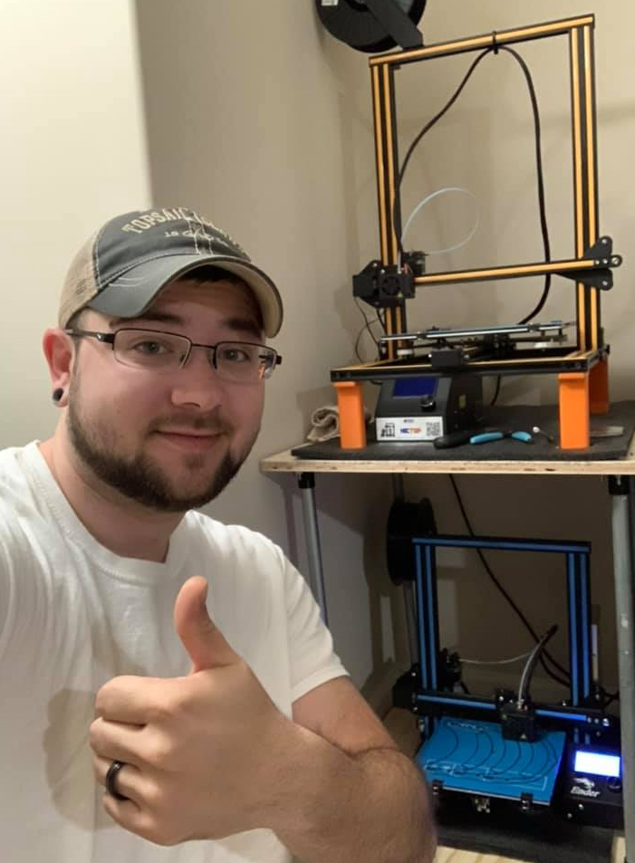Cameron Sutton giving thumbs up with 3D printer in background