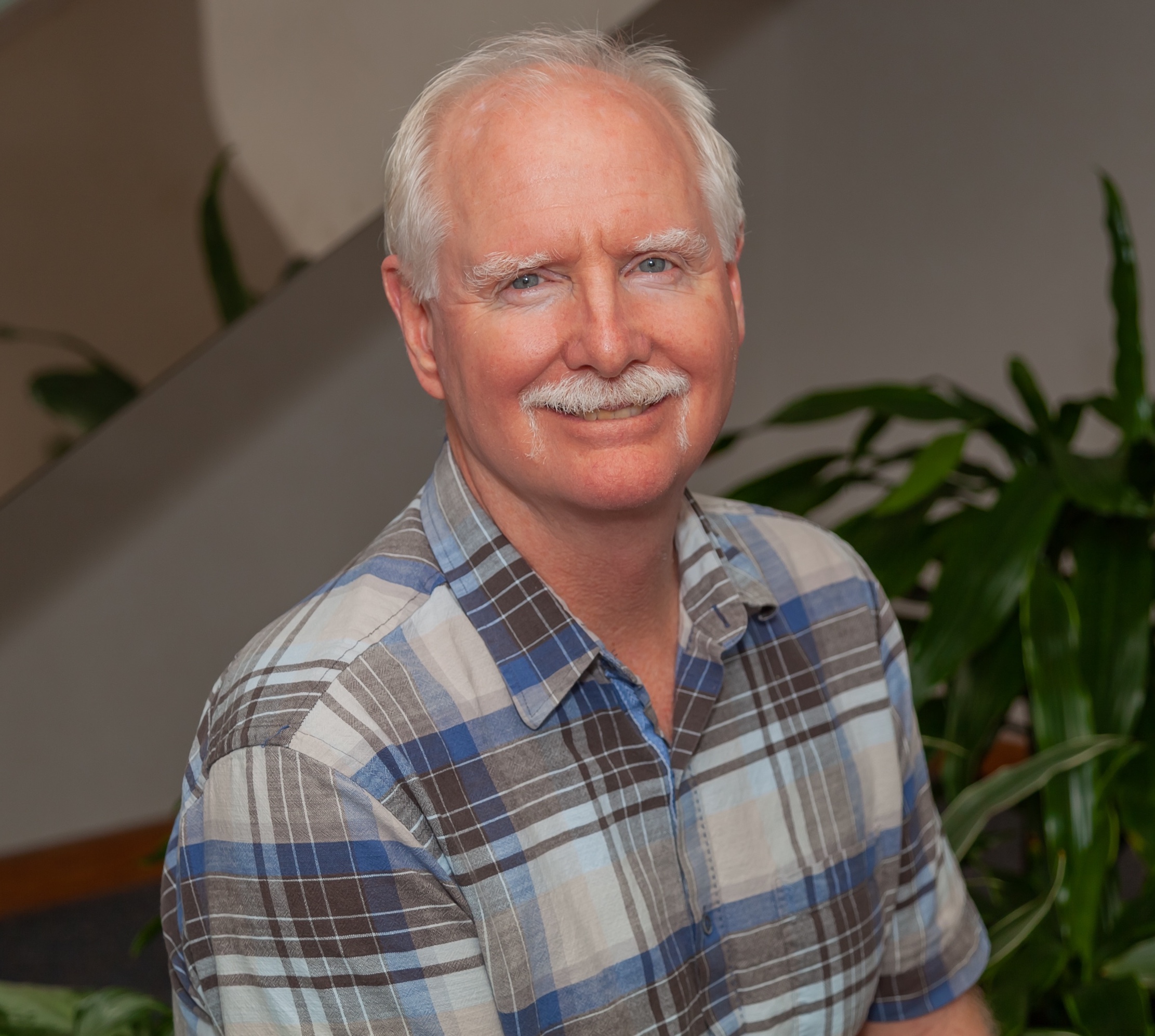 Bob May, photo taken in CEBAF Center building on JLab campus, plants in background