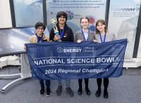 A group of 4 students hold a trophy. 