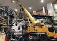 A mobile crane lifts the giant BigByte spectrometer yellow and blue magnet in Hall A
