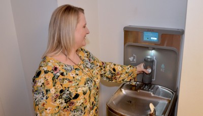 Woman fills a generic water bottle from an Elkay Water Refill stations.