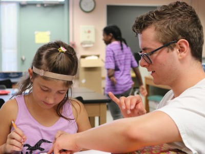 A camp counselor helps a student with an activity at the 2019 Deaf Science Camp