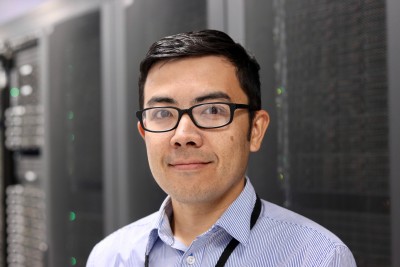 Nobuo Sato stands in front of a supercomputer in Jefferson Lab's Data Center
