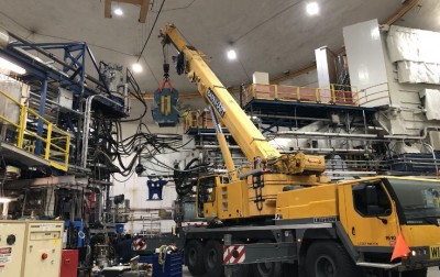 A mobile crane lifts the giant BigByte spectrometer yellow and blue magnet in Hall A