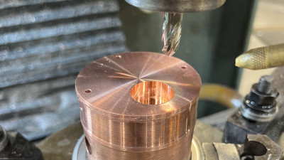 A remade chopper coupler - a copper cylinder attached to a stainless steel joint - shown here in a drill press