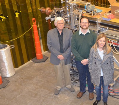 College of William and Mary graduate student Matthew Burton (center left), pauses for a photo in Jefferson Lab's SRF Institute with his Advisor, R. Ale Lukaszew (center right), the W&M Virginia Microelectronics Consortium Distinguished Professor of Physics, and his Jefferson Lab Advisor, Larry Phillips. Behind them is the cavity deposition system Burton is using in his research which is aimed at improving superconducting radiofrequency thin-film capabilities. A Department of Energy Office of Science Graduat